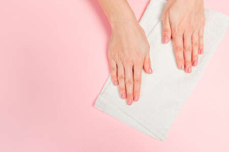 Beautiful young woman's hands with  white care  towel   on pastel pink background - Imageの写真素材