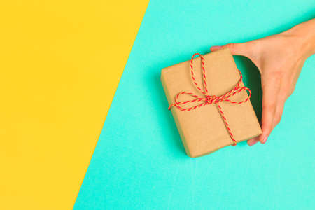 Woman presenting gift box top view on pastel  background .Giving presents concept  for Mother's Day, Women's Day or any other holiday or celebrationの写真素材