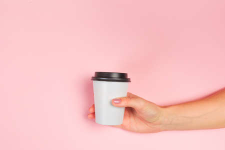 female  manicure. Beautiful young woman's hands holding coffee on pastel pink backgroundの写真素材