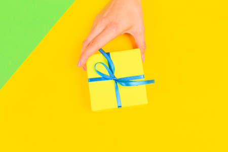 Woman presenting gift box top view on pastel  background .Giving presents concept  for Mother's Day, Women's Day or any other holiday or celebrationの写真素材