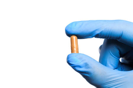 Doctor hand in sterile gloves holding  pill isolated on white background  close up viewの写真素材