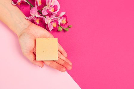 female  manicure. Beautiful young woman's hands holding a soap on pastel pink backgroundの写真素材