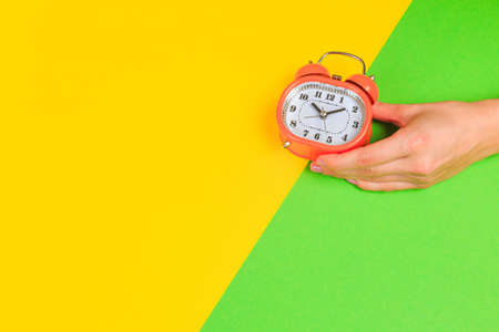 Beautiful young woman's hands with alarm clock  on pastel  background - Imageの写真素材