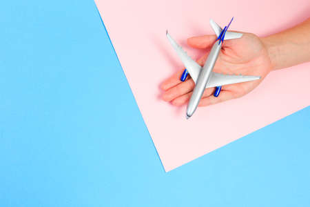 Beautiful young woman's hands holding plane    on pastel  background - Imageの写真素材