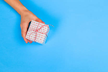 Woman presenting gift box top view on pastel  background .Giving presents concept  for Mother's Day, Women's Day or any other holiday or celebrationの写真素材