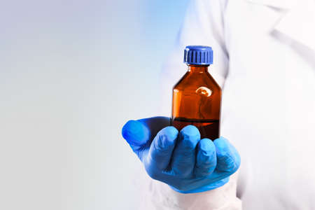 Doctor hand in sterile gloves holding glass vial isolated on white backgroundの写真素材