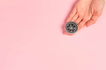 Beautiful young woman's hands holding  compass on pastel pink background - Image
