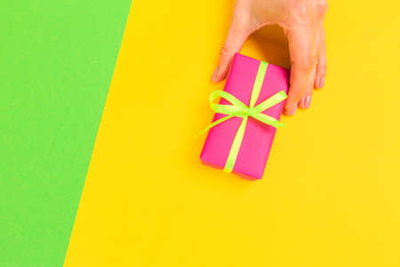 Woman presenting gift box top view on pastel  background .Giving presents concept  for Mother's Day, Women's Day or any other holiday or celebrationの写真素材