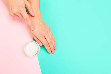 female  manicure. Beautiful young woman's hands with cream  on pastel background - Imageの写真素材