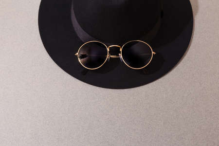 Black felt hat with round sunglasses on grey background - Image