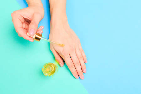 Beautiful young woman's hands with  oil bottle  on pastel background - Imageの写真素材