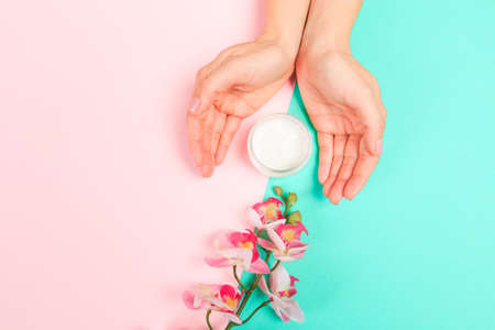 female  manicure. Beautiful young woman's hands with cream  on pastel background - Image