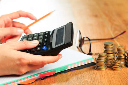 female hands working on a calculator on wooden background  - Imageの写真素材