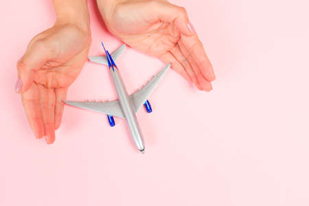 Beautiful young woman's hands holding plane    on pastel  background - Imageの写真素材