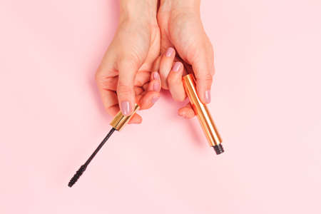 Beautiful young woman's hands holding  mascara on pastel pink background - Imageの写真素材