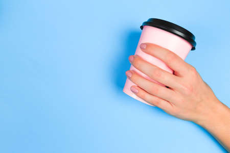 female  manicure. Beautiful young woman's hands holding coffee on pastel pink background