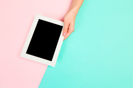 Beautiful young woman's hands holding frame for your text place  on pastel  background - Image