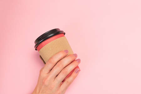 female  manicure. Beautiful young woman's hands holding coffee on pastel pink backgroundの写真素材