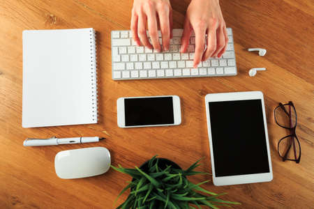 Female hands working on wooden work place with modern gadgets  top view - Imageの写真素材