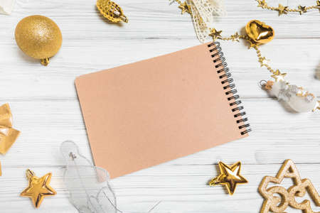 golden christmas decorations and notebook on white background. Flat lay, top view, copy spaceの写真素材