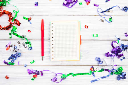 Festive decorations and notebook with wish list on white rustic table, flat lay style. Planning...