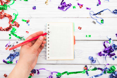 Festive decorations and notebook with wish list on white rustic table, flat lay style. Planning...
