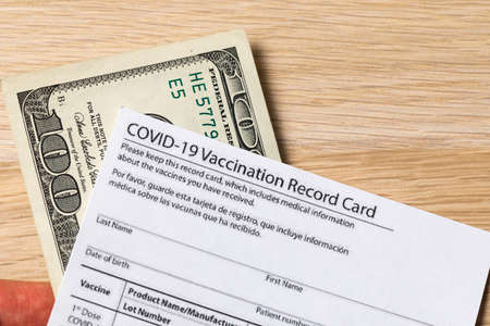 Covid-19 vaccination card and cash moneyの写真素材