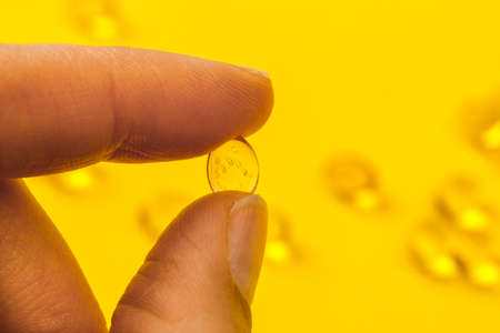 hand holdind  oil filled capsules suitable for: fish oil, omega 3, omega 6, omega 9,  vitamin A, vitamin D, vitamin D3, vitamin Eの写真素材