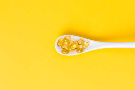 Close up of oil filled capsules on spoon suitable for: fish oil, omega 3, omega 6, omega 9, vitamin A, vitamin D, vitamin D3, vitamin Eの写真素材