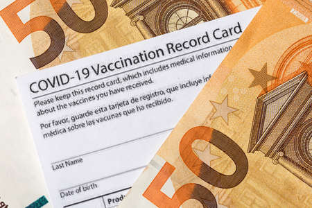 Covid-19 vaccination card and cash moneyの写真素材
