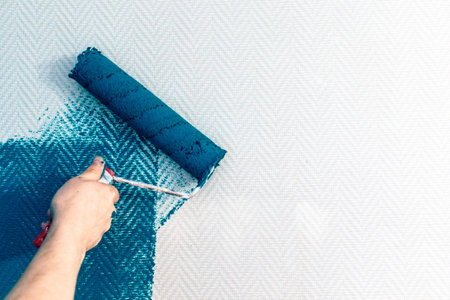 hand painting wall with paint roller. Painting apartment, renovating with color paint