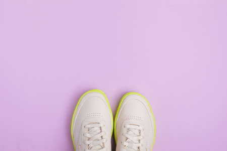 beige neon-soled sneakers on color background