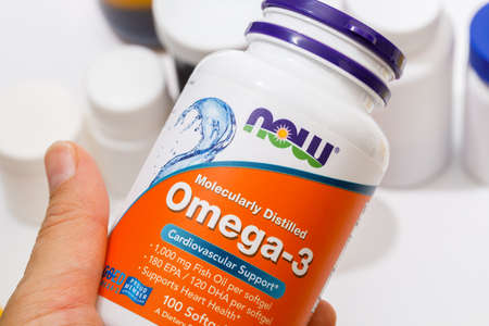 Krasnodar, Russian Federation - December 10, 2021 Bottle of vitamin Omega3  by NOW in woman hand.のeditorial素材