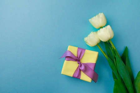 Gift box and spring flowers on color background. Stylish soft image of spring flowers. Happy women's...