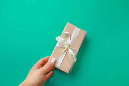 Woman's hand holding Gift box on color background. Happy women's day. Happy Mothers day.Hello Springの写真素材
