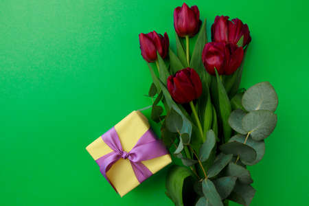 Gift box and spring flowers on color background. Stylish soft image of spring flowers. Happy women's...
