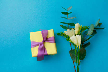 Gift box and spring flowers on color background. Stylish soft image of spring flowers. Happy womens...