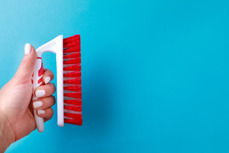 womans hand holding Cleaning brush  on color background. Brush for cleaning clothes, carpets. Tool...