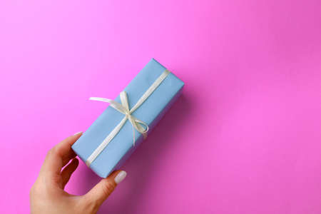 Woman's hand holding Gift box on color background. Happy women's day. Happy Mothers day.Hello Springの写真素材