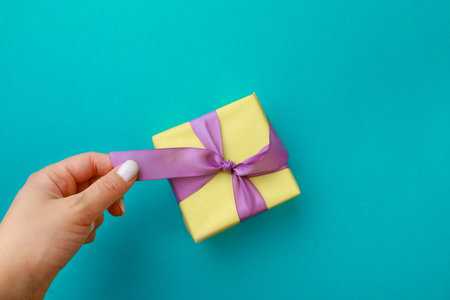 Womans hand holding Gift box on color background. Happy womens day. Happy Mothers day.Hello Springの写真素材