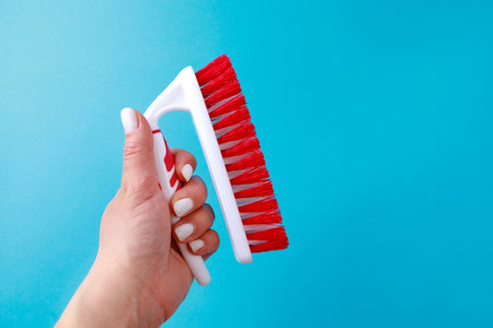 womans hand holding Cleaning brush  on color background. Brush for cleaning clothes, carpets. Tool for home care.の写真素材
