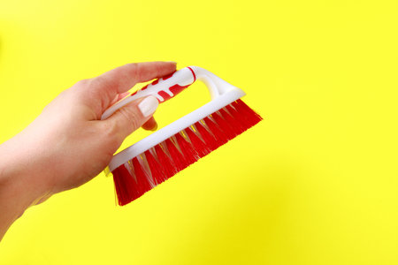 hand holding Cleaning brush  on color background. Brush for cleaning clothes, carpets. Tool for home care.の写真素材