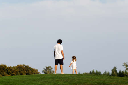 On a sunny warm day, a young family with a daughter have a good time in the park.の写真素材