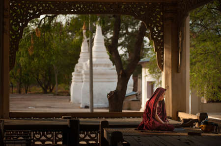 BAGAN, MYANMAR - MAY 3 , 2013: Southeast Asian neophyte praying with candle light in a Buddihist temple on MAY 3 , 2013 in Bagan, Myanmar.のeditorial素材