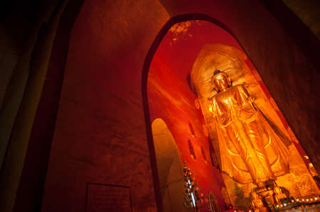 BAGAN, MYANMAR - MAT 4: Standing Buddha Kassapa at south facing part of the Ananda temple adorned by believers by sticking goledn leaves on statue on May 4, 2013 in Bagan, Myanmar.のeditorial素材