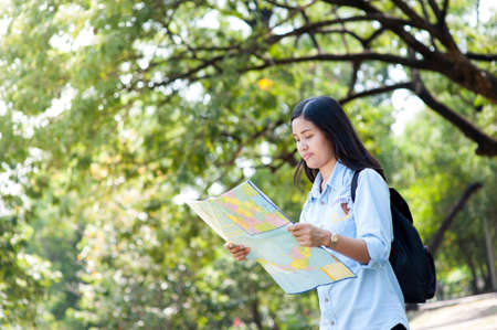 Women traveler with backpack checks map to find directions in the park of Thailand,active people lifestyleのeditorial素材