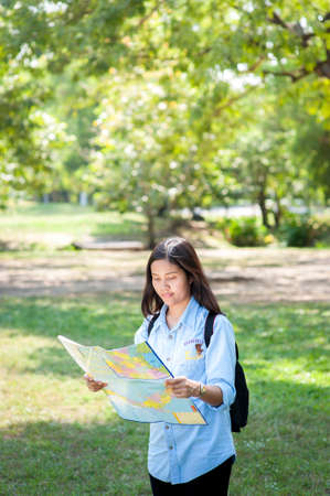 Women traveler with backpack checks map to find directions in the park of Thailand,active people lifestyleのeditorial素材