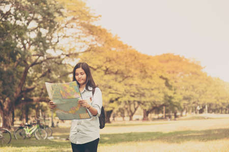 Women traveler with backpack checks map to find directions in the park of Thailand,active people lifestyleの写真素材