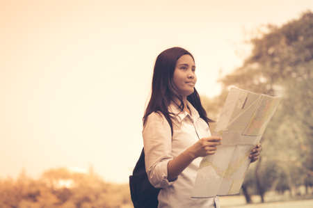 Women traveler with backpack checks map to find directions in the park of Thailand,active people lifestyleの写真素材