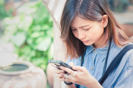 Close-up of female hands using modern smart phone while working,Young woman using a touchscreen smartphone with copy spaceの写真素材